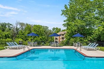 A swimming pool surrounded by lawn chairs and umbrellas.